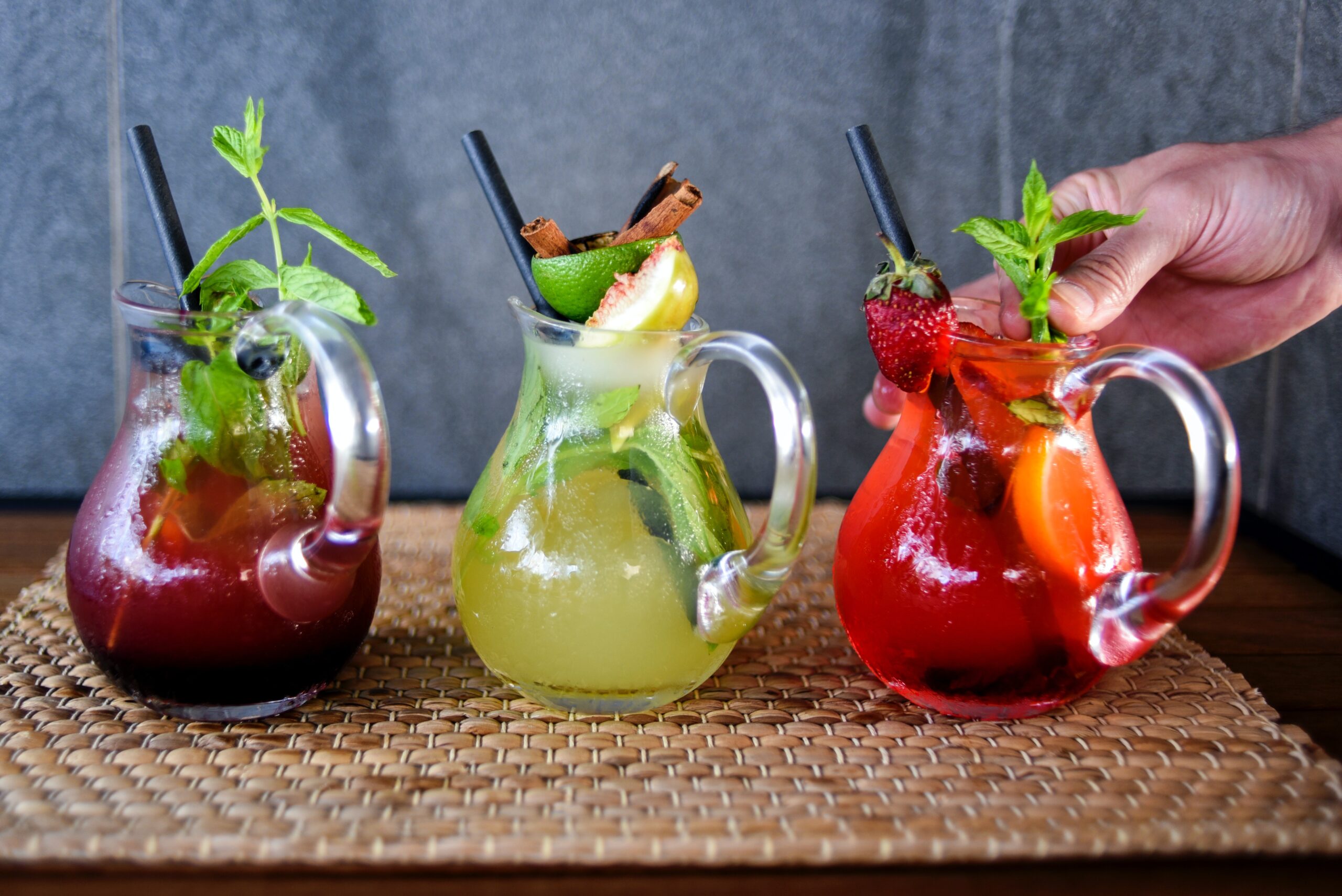 Drei Krüge mit Getränken in Dunkelrot, Limegreen und Erdbeerrot, reichlich dekoriert mit Früchten & Co